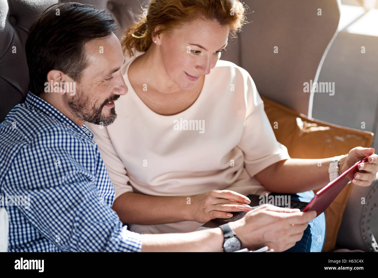 Side view of couple using laptop on couch Stock Photo - Alamy