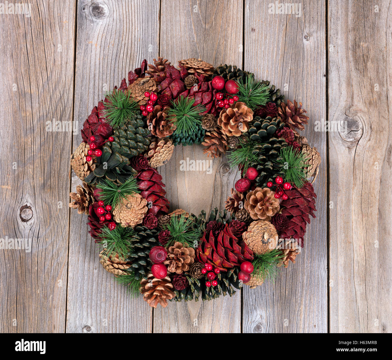 Holiday evergreen and berry wreath on top of rustic wood Stock Photo