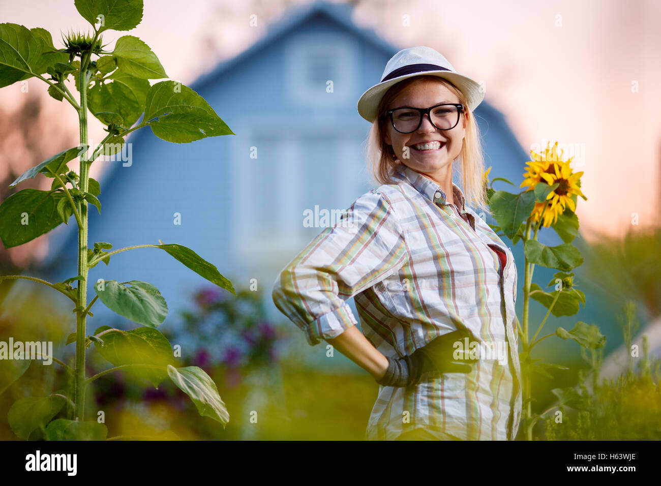 Happy young woman gardener posing in garden before her cottage in ...