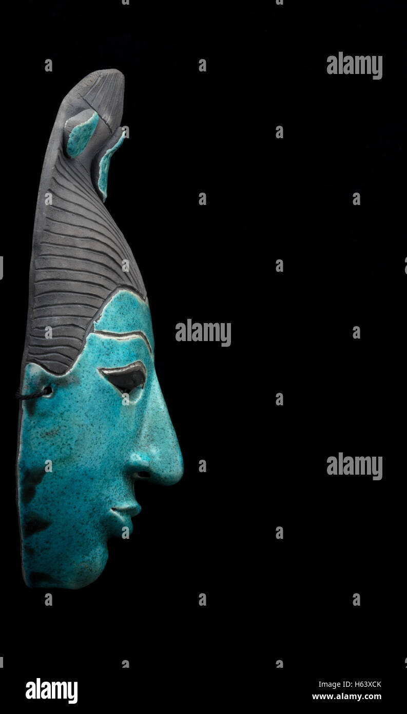blue ceramic mask of an Asian face on black background Stock Photo