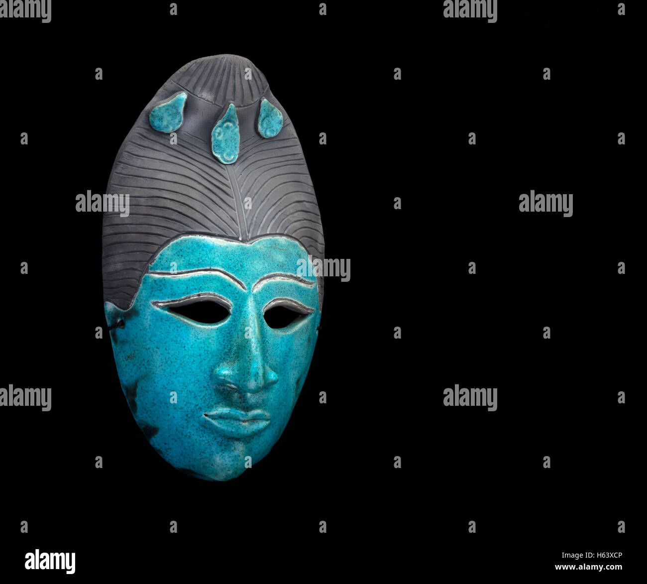blue ceramic mask of an Asian face on black background Stock Photo