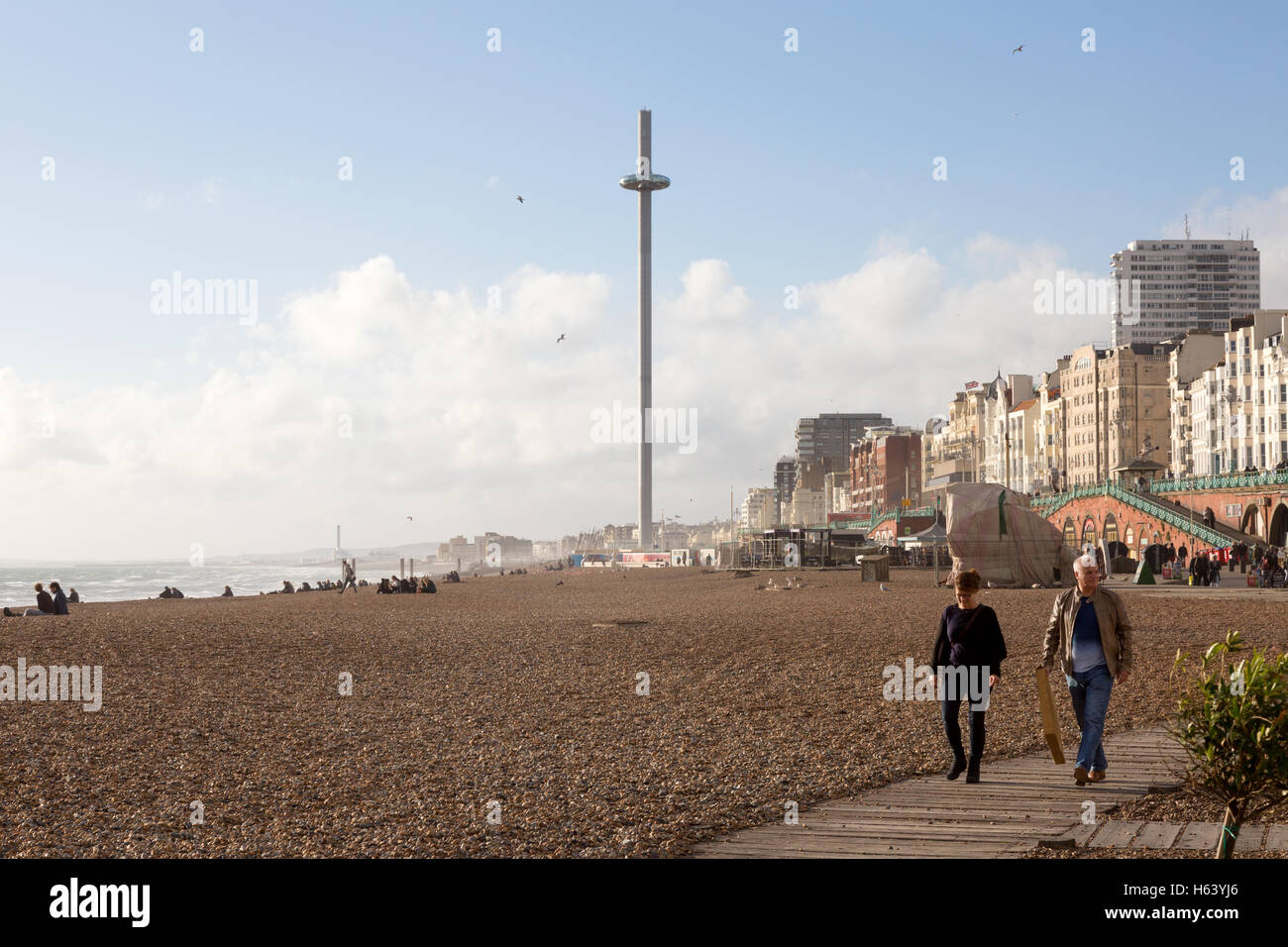People walking on Brighton promenade, with the i360 observation tower in the background, Brighton, East Sussex UK Stock Photo