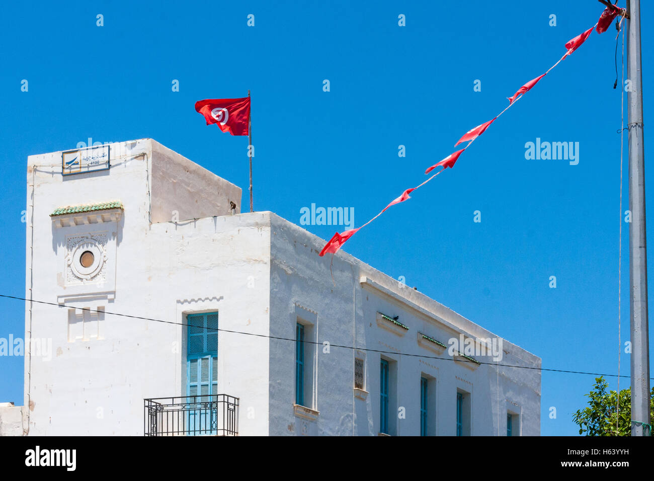 white office building with red flags in Houmt Souk, Djerba Tunisia Stock Photo