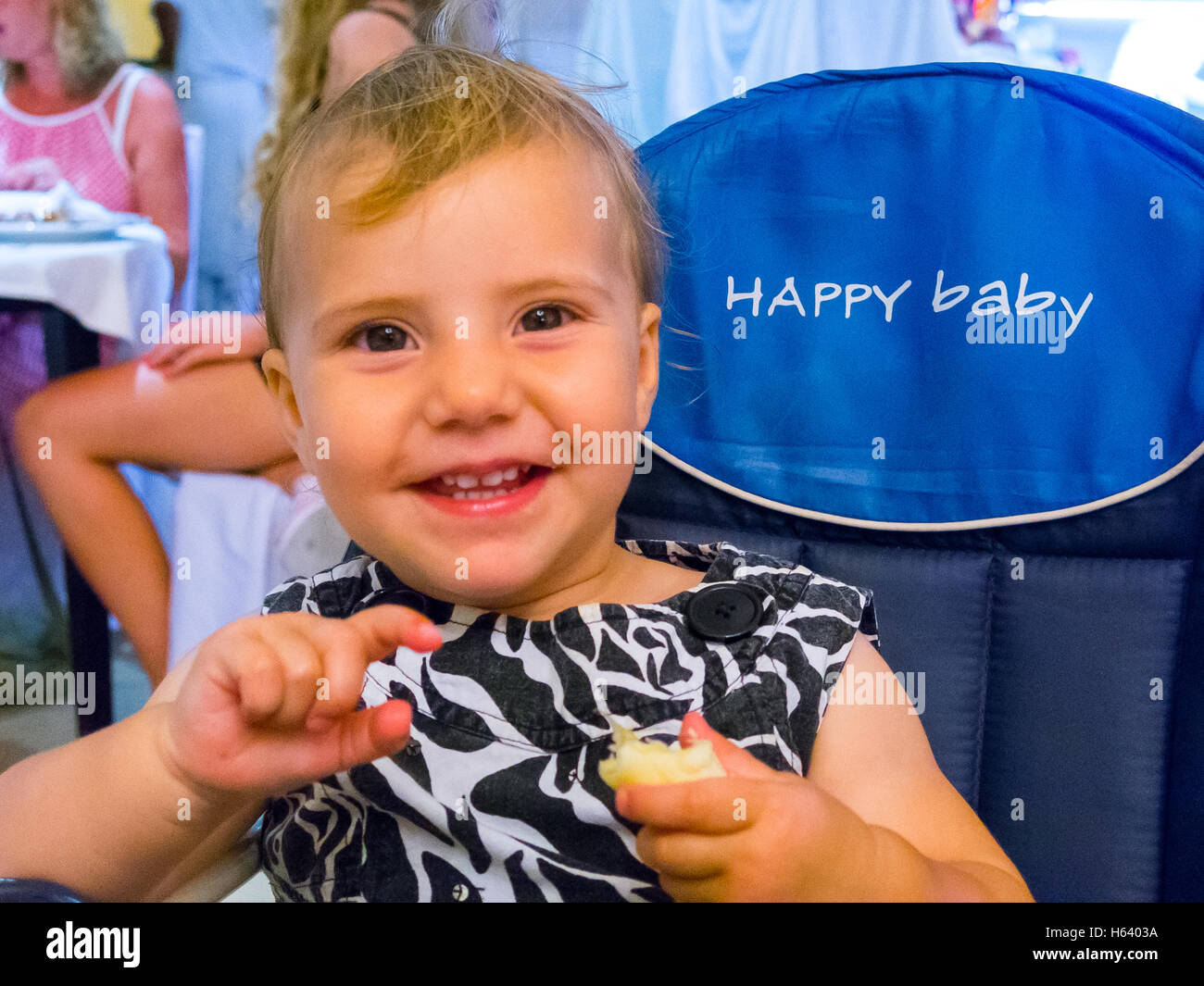 girl eating in high chair Stock Photo