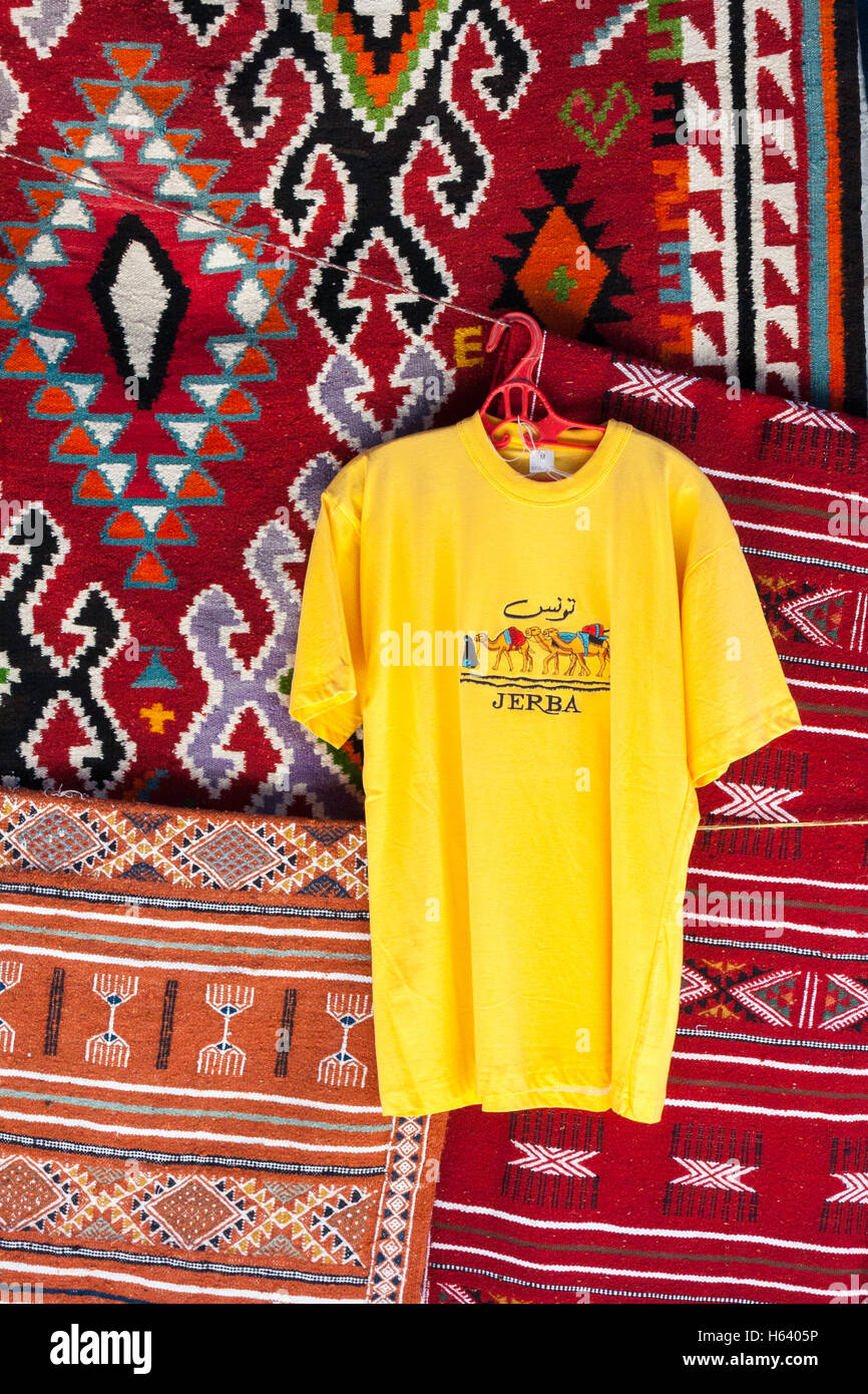 Yellow Jerba tee shirt hanging on colorful rugs Stock Photo