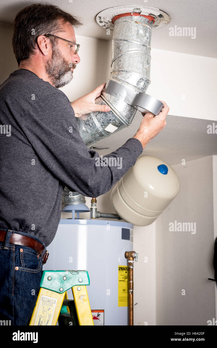 Master plumber works on a hot water heater duct Stock Photo