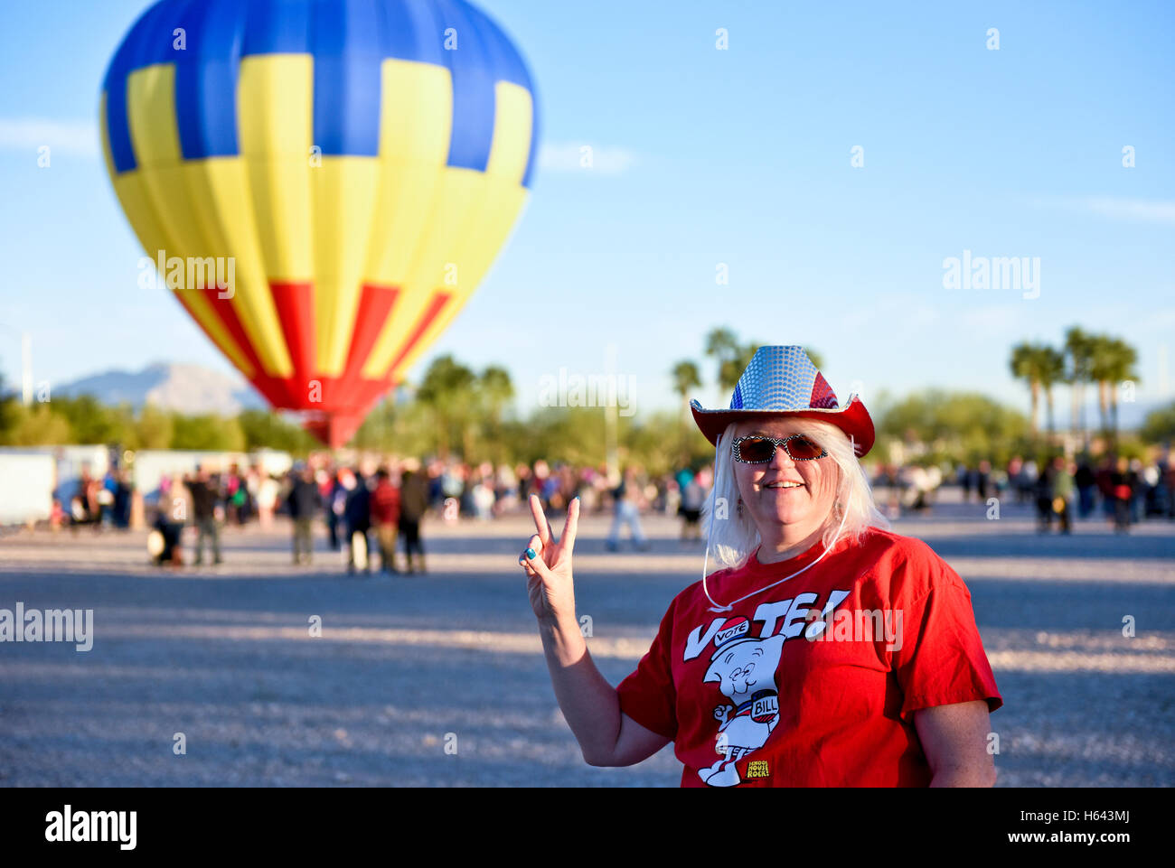 A lady holding up a peace sign hand gesture after voting early in Nevada with a hot air balloon in the background Stock Photo