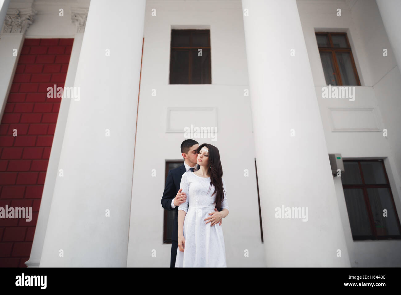 Beautiful couple, bride and groom posing near big white column Stock ...