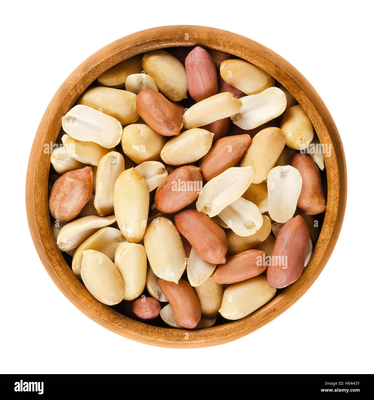 Shelled peanuts in wooden bowl on white background. Dry roasted Arachis hypogaea, also called groundnut and goober. Stock Photo
