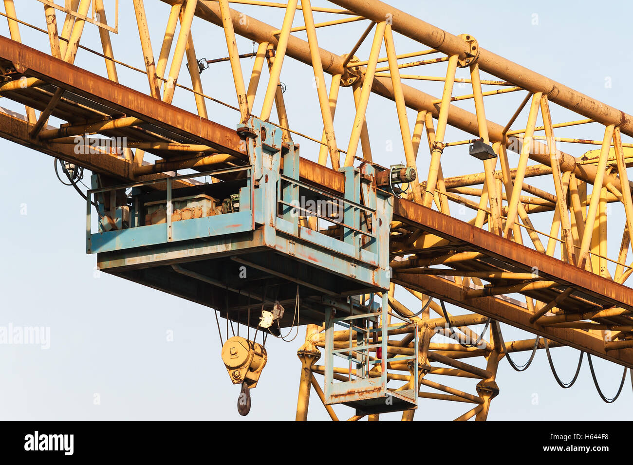 Yellow gantry crane with winch and hook over bright blue sky Stock Photo