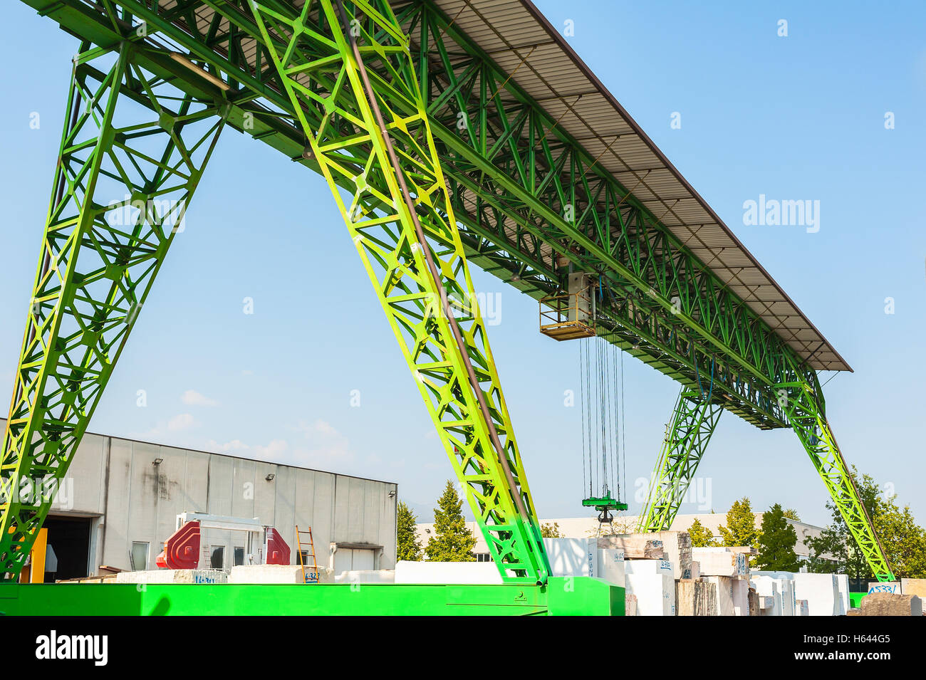 Green gantry crane at work in a warehouse of marble blocks Stock Photo