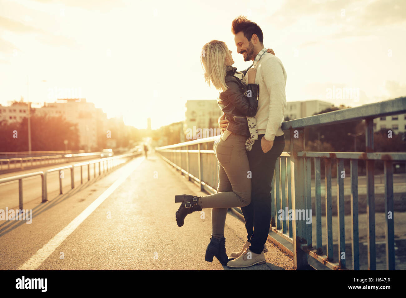 Couple kissing dating on bridge during sunset Stock Photo - Alamy