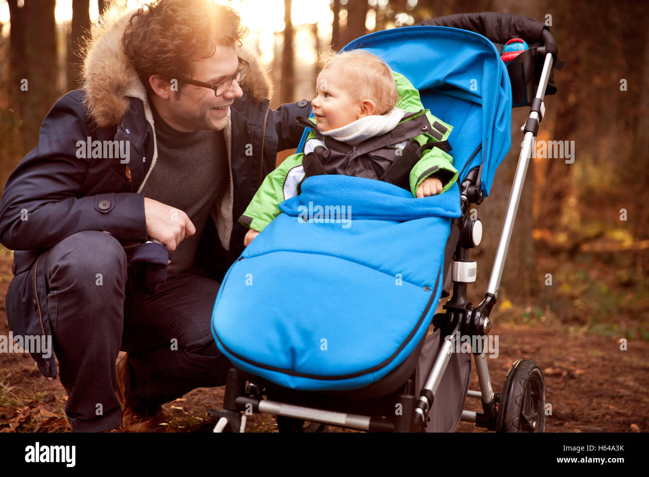 Father smiling at son in buggy in forest Stock Photo