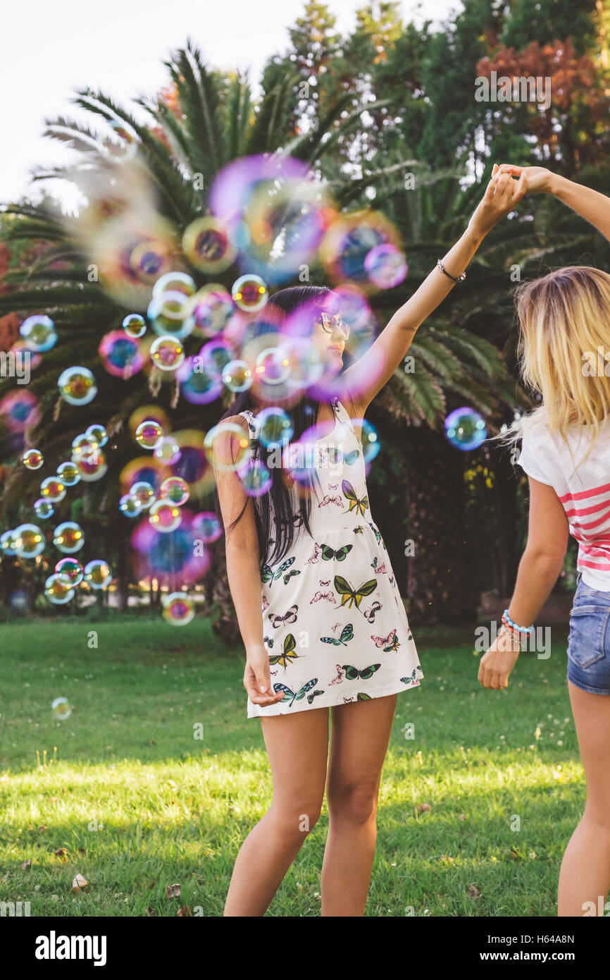 Female friends having fun with soap bubbles in park Stock Photo - Alamy