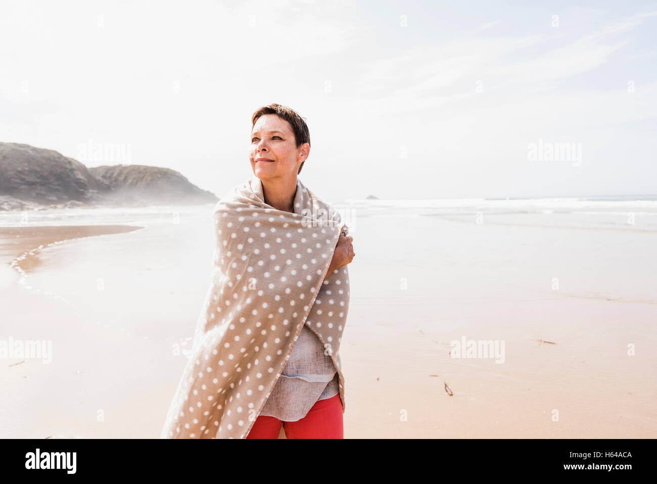 Mature woman wrapped in a blanket on the beach Stock Photo Alamy