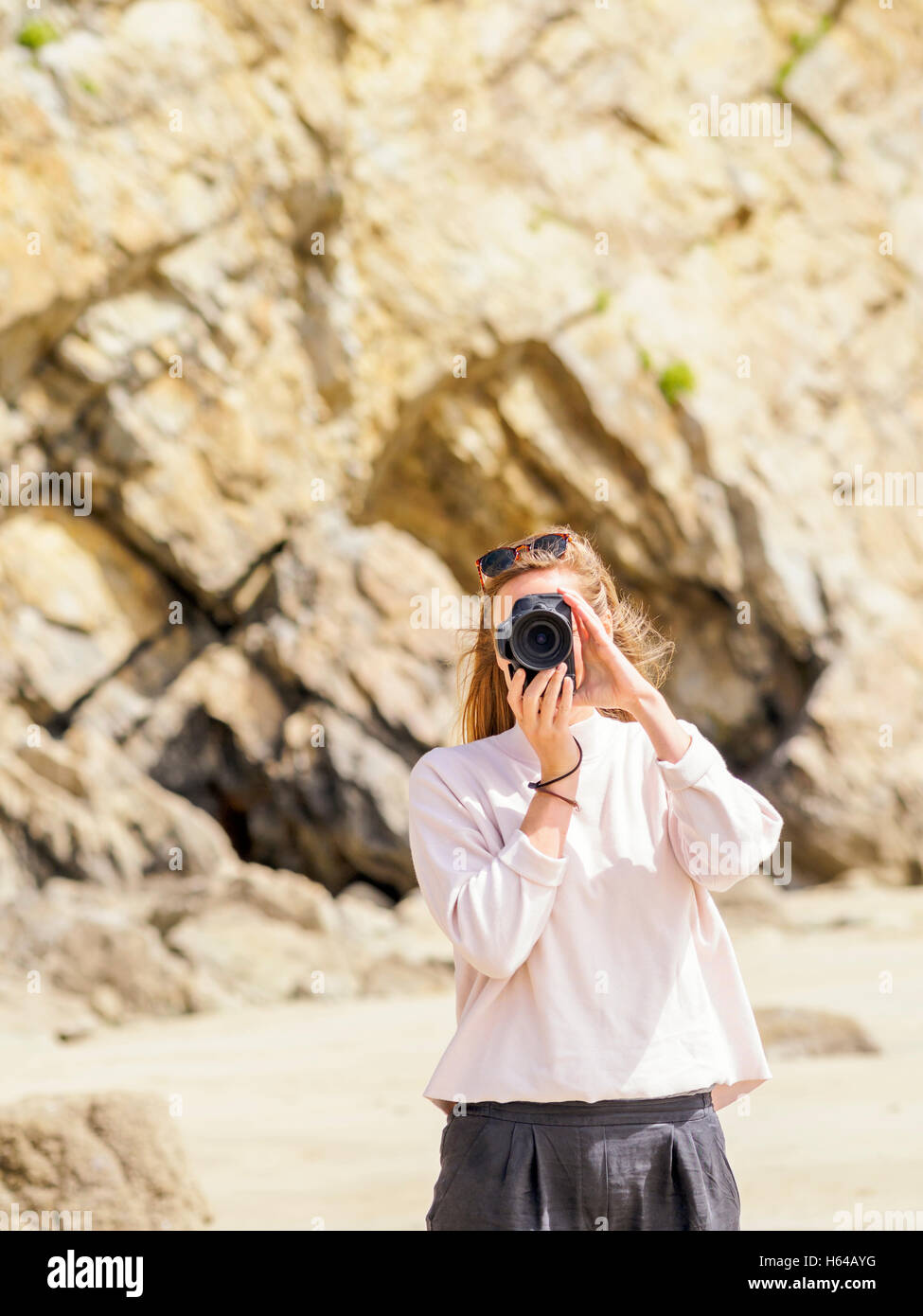 Woman standing at the beach, taking a picture with camera Stock Photo