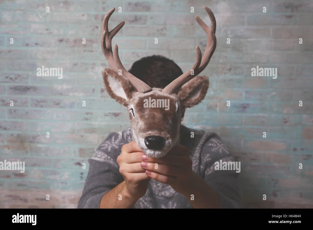 Young man holding artificial deer head in front of his face Stock Photo -  Alamy