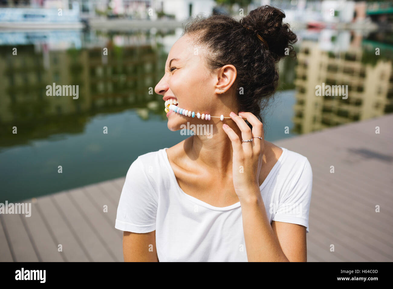 Happy young woman biting in candy necklace Stock Photo