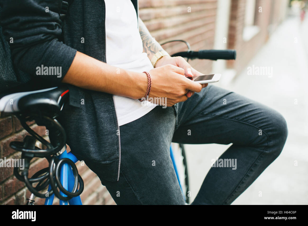 Teenager with a bike in the city, using smartphone Stock Photo