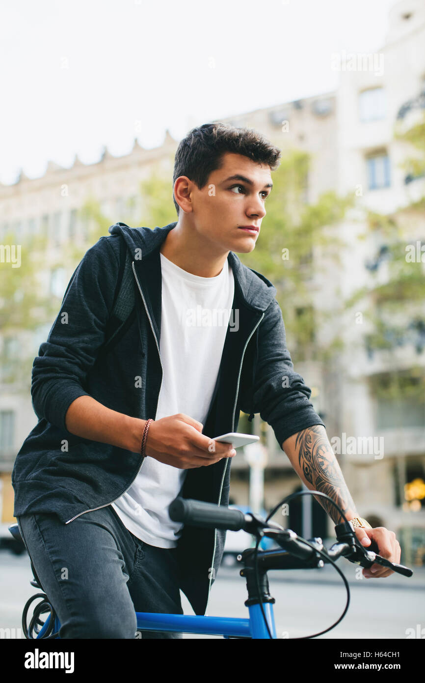 Teenager with a fixie bike in the city, smartphone Stock Photo