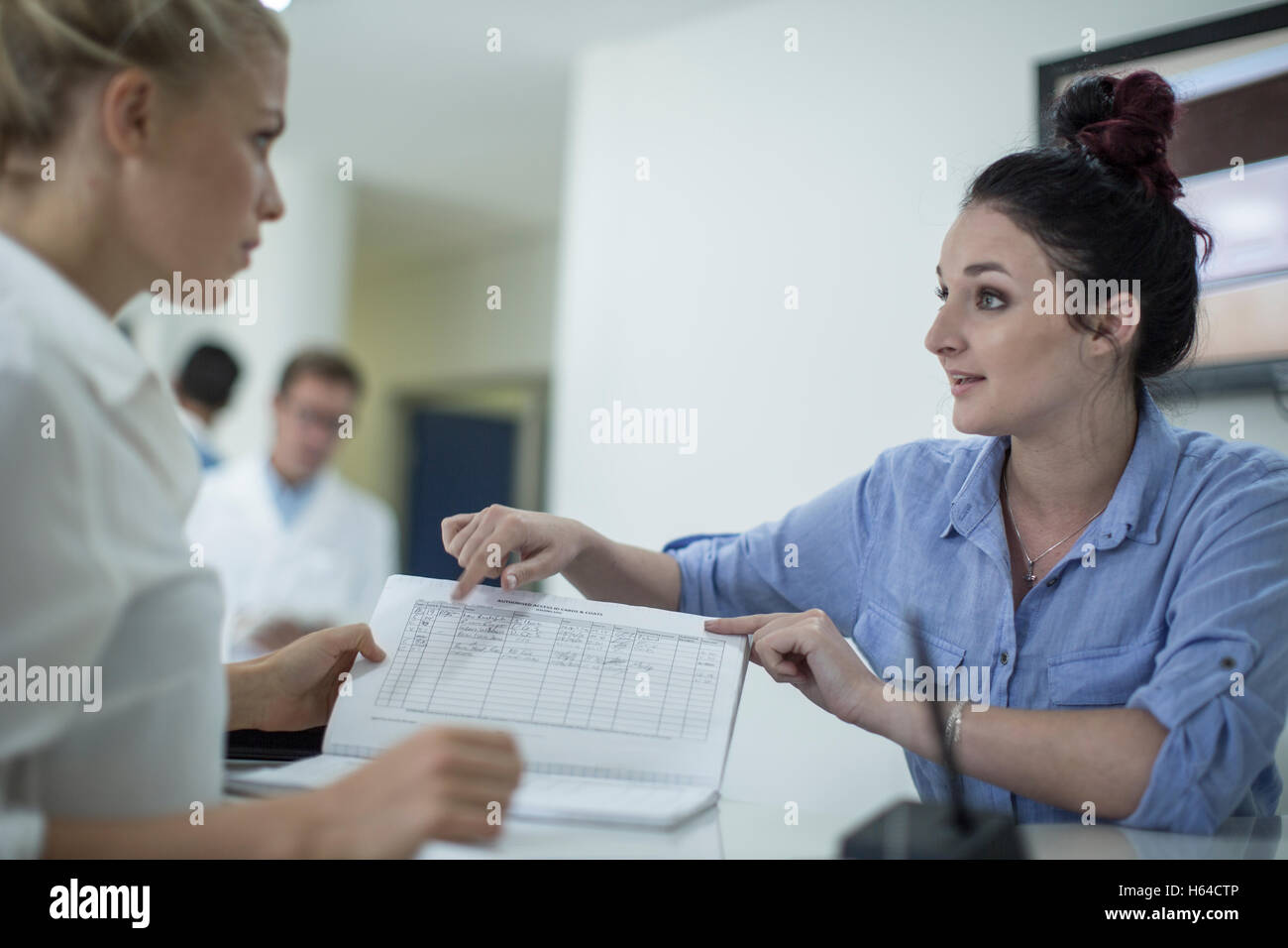 Two women with book at reception Stock Photo