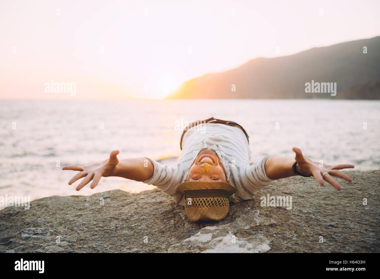 Greece, Cylcades Islands, Amorgos, happy man enjoying the sunset next to the sea Stock Photo