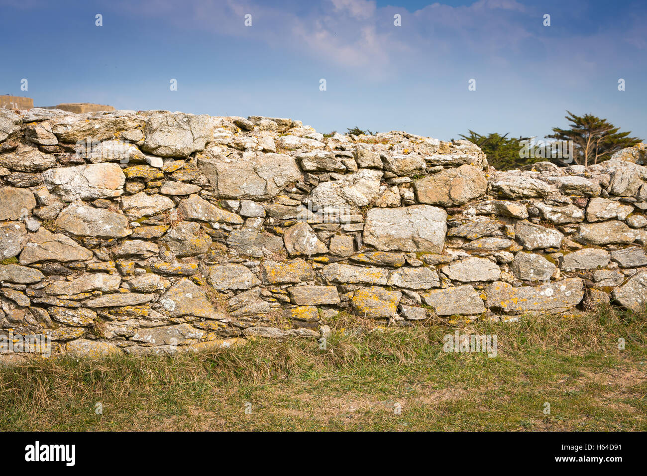 old stone wall on grass with blue sky Stock Photo - Alamy