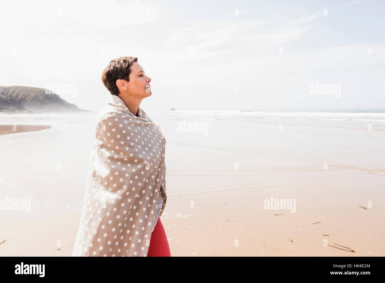 Mature woman wrapped in a blanket on the beach Stock Photo Alamy