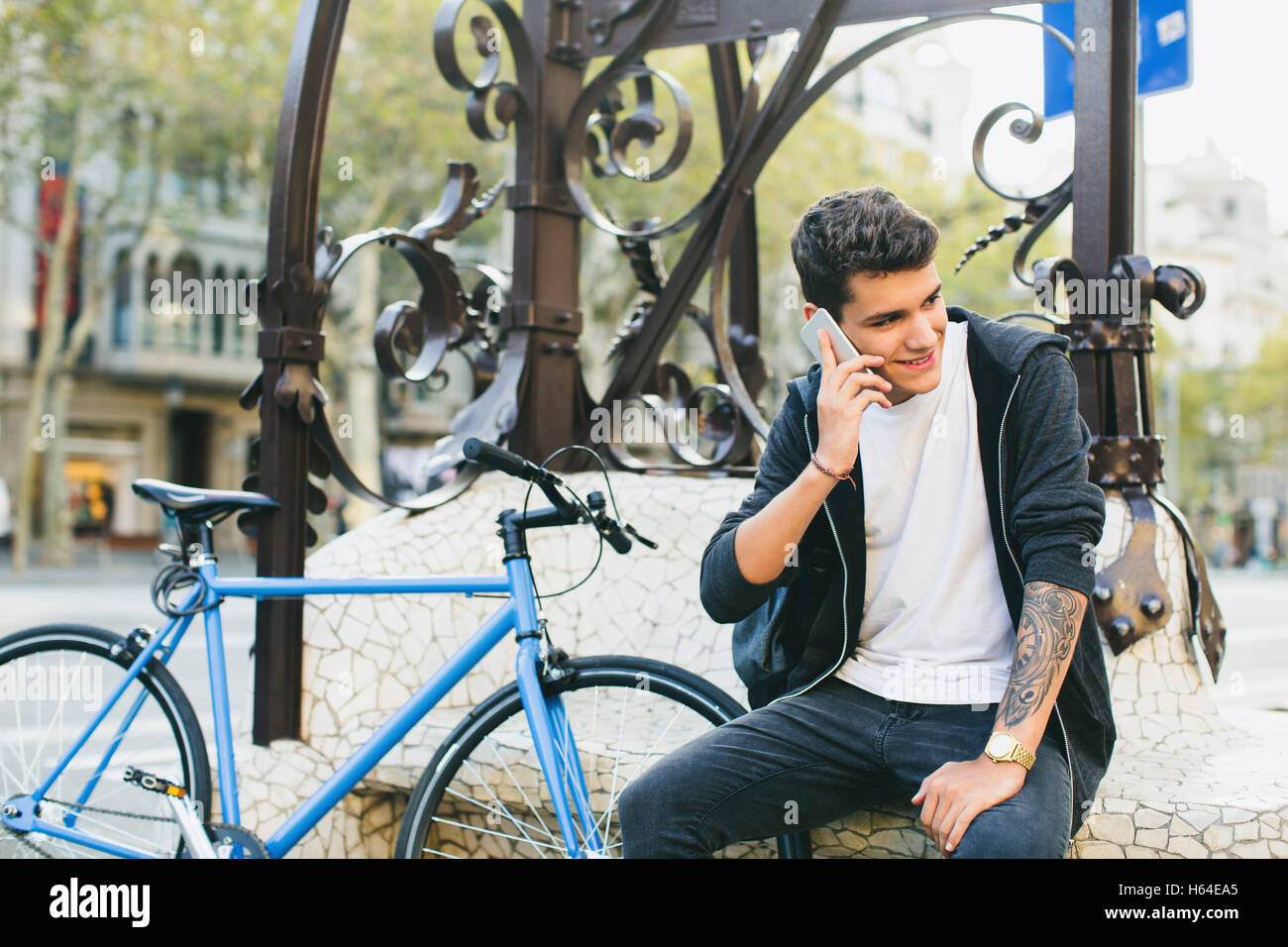 Teenager with a bike in the city, using smartphone Stock Photo