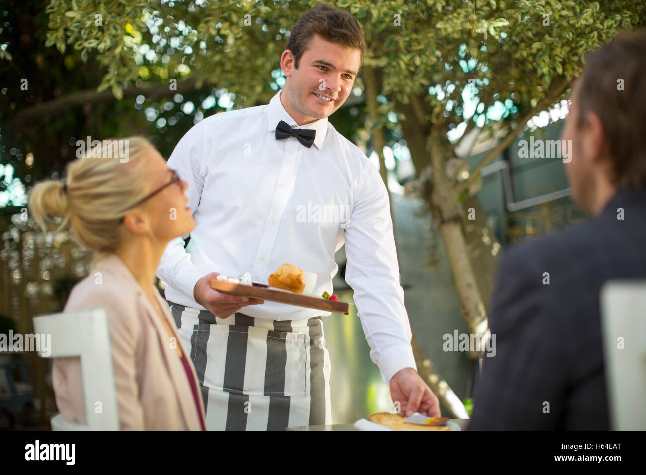 Waiter serving food at table for two Stock Photo - Alamy
