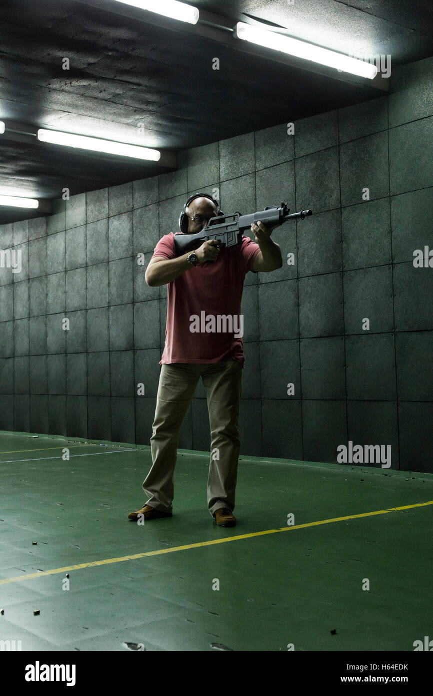 Man aiming with a tactical weapon in an indoor shooting range Stock