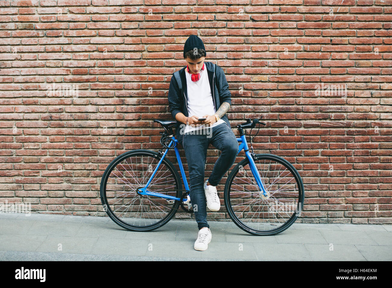 Teenager with a fixie bike, using smartphone Stock Photo