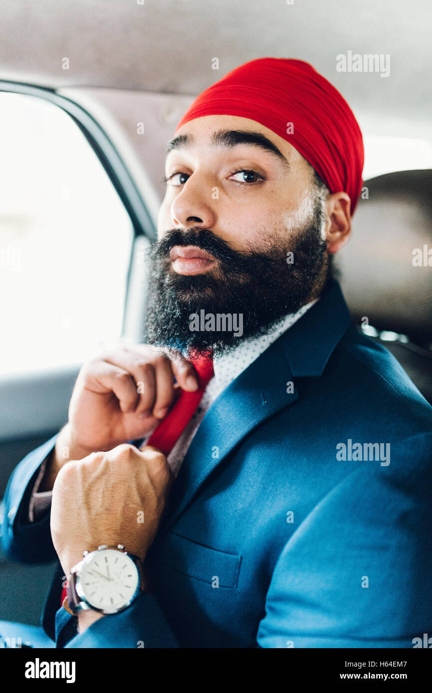 Indian businessman binding tie in a taxi Stock Photo