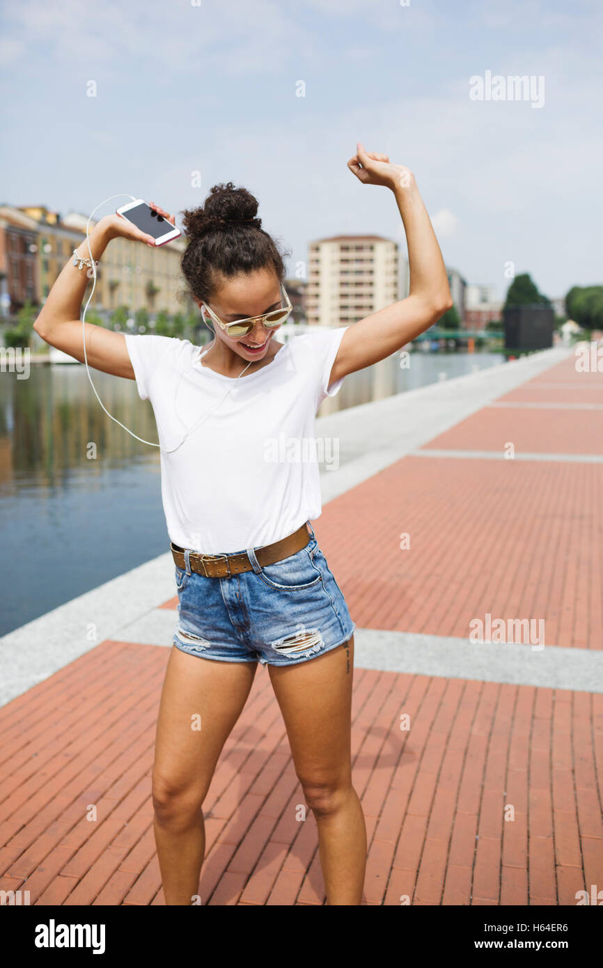 Happy young woman listening to music and dancing at the riverside Stock ...