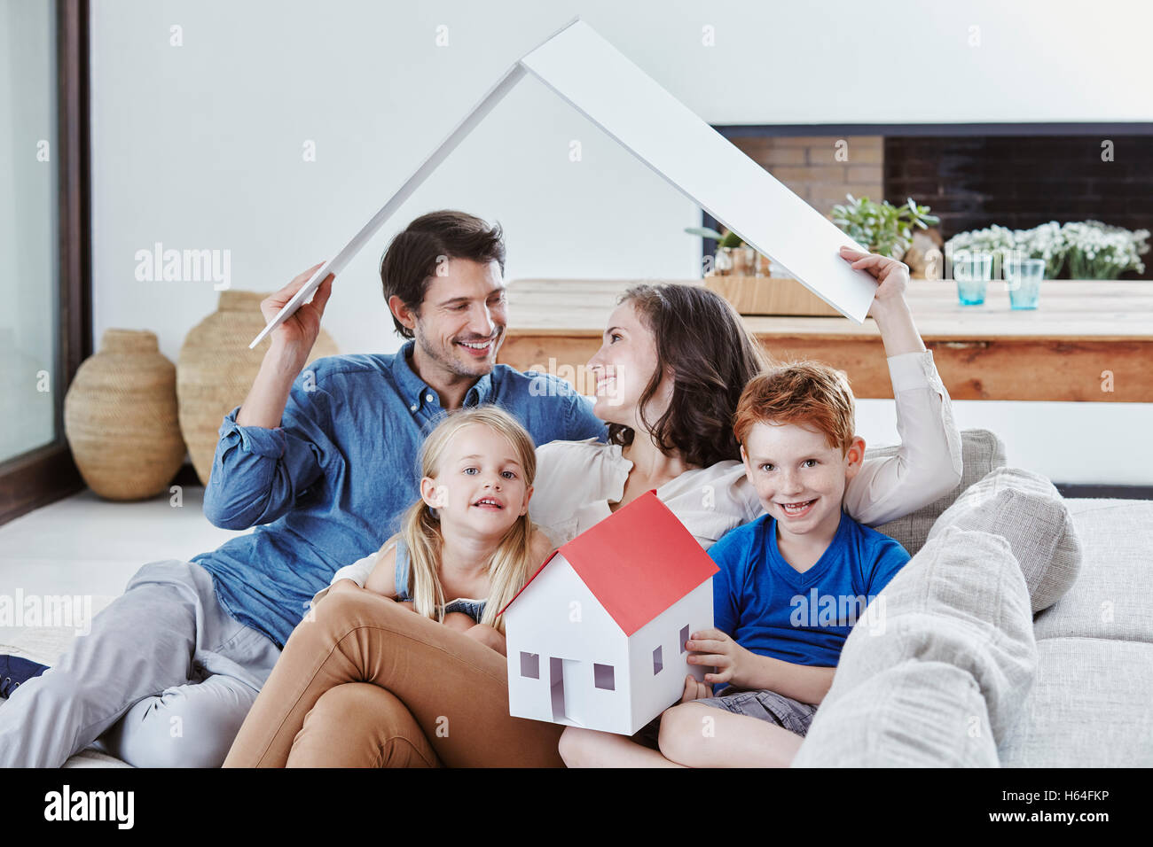 Happy family of four with house model in living room Stock Photo