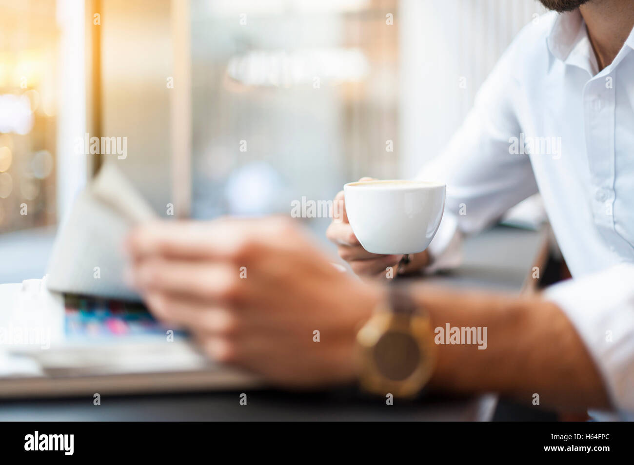 Close-up of businessman with cup of coffee reading newspaper in a cafe Stock Photo