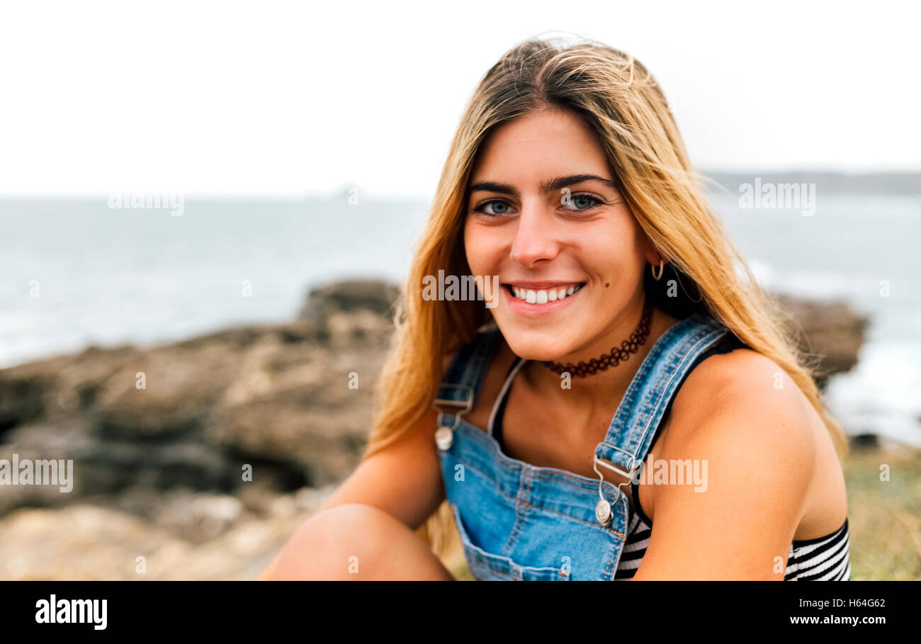 Portrait of smiling teenage girl sitting at the coast Stock Photo - Alamy