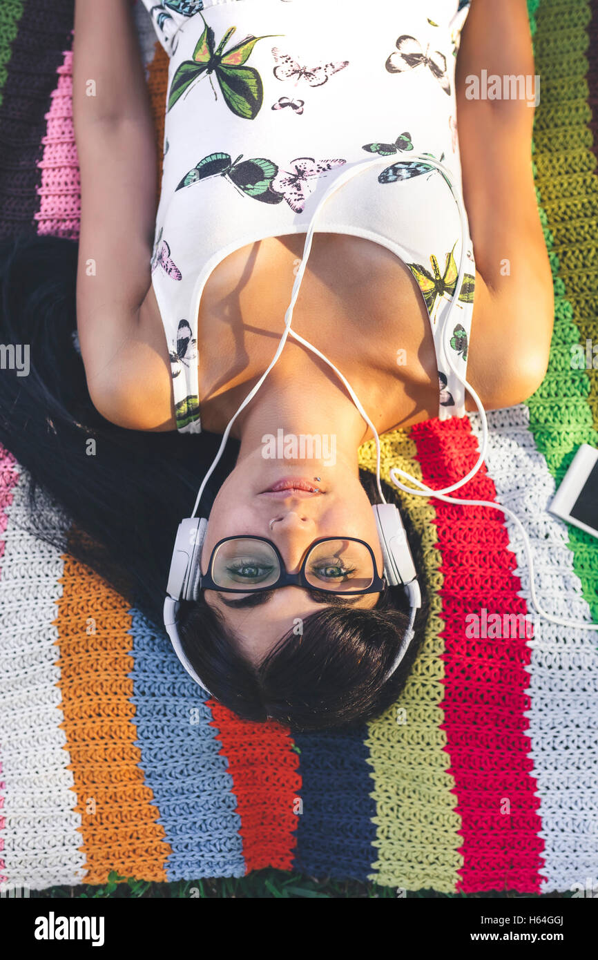 Young woman lying on blanket listening to music Stock Photo - Alamy