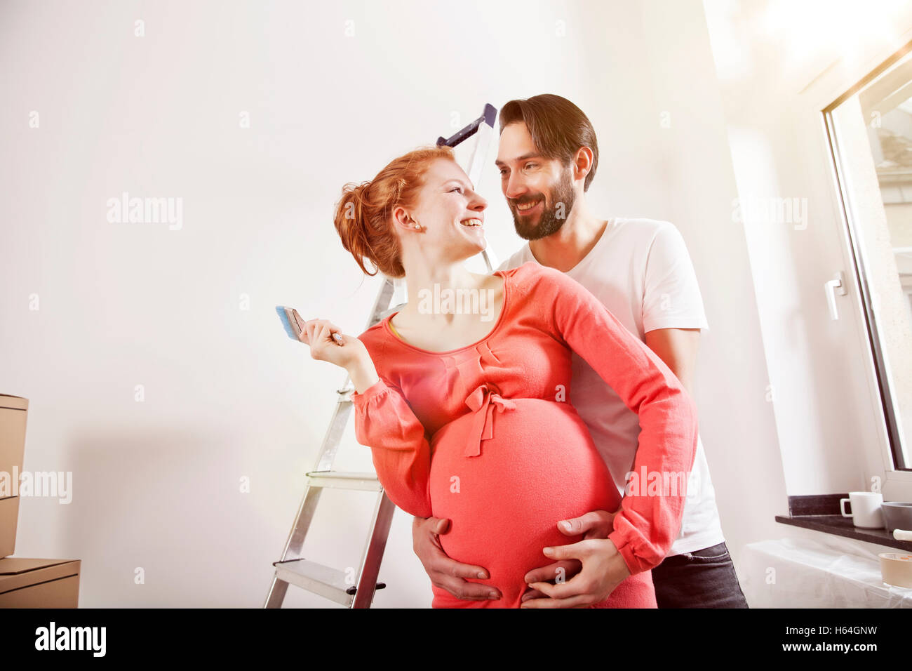 Happy man hugging pregnant woman while renovating new home Stock Photo ...