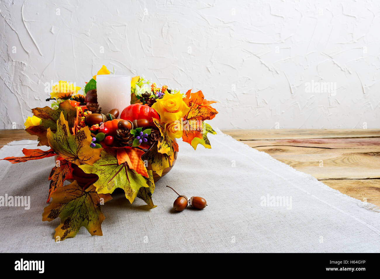 Thanksgiving centerpiece with decorated candle and silk fall leaves . Thanksgiving background with fall decor. Fall background. Stock Photo