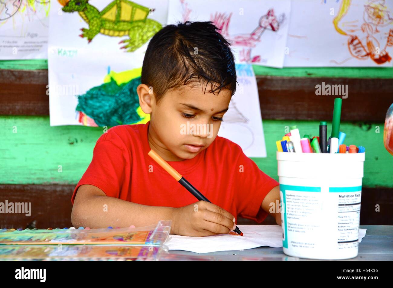 Young boy at table writing and making art. Stock Photo