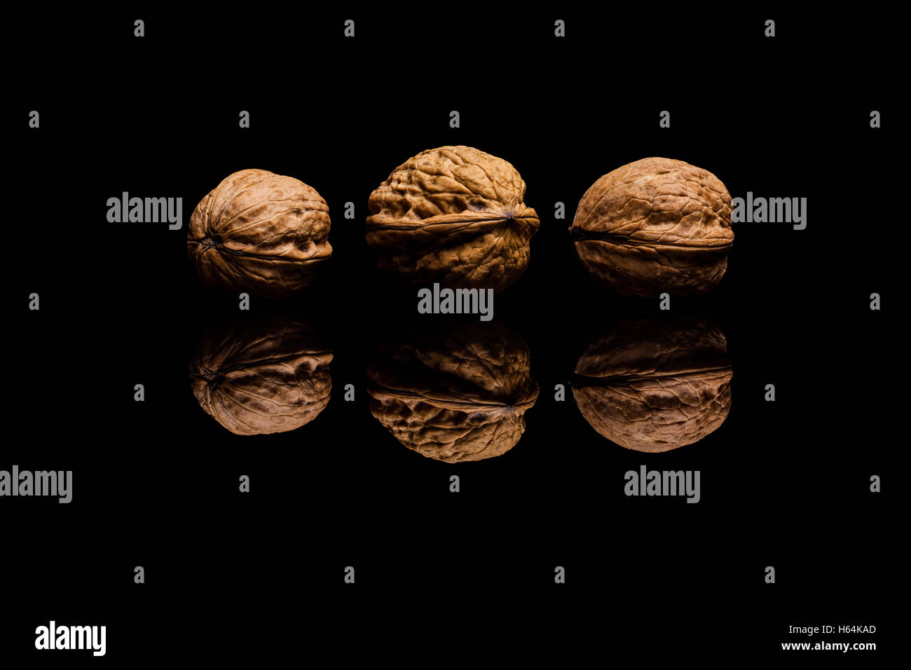 Three whole walnuts isolated on black reflective background Stock Photo