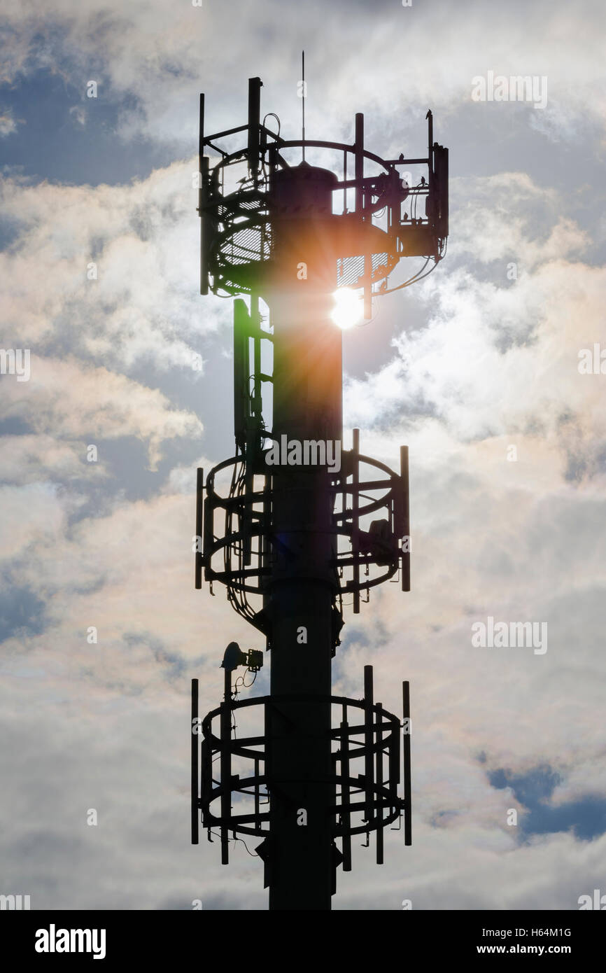 Cell tower mast in silhouette with the sun shining from behind. Stock Photo