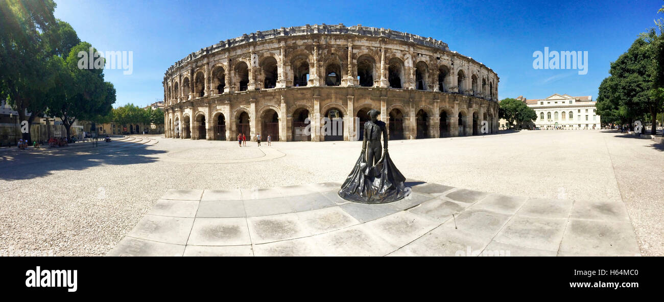 The Roman amphitheater (Roman Arena) and bullfighter statue in Nimes, France. Stock Photo