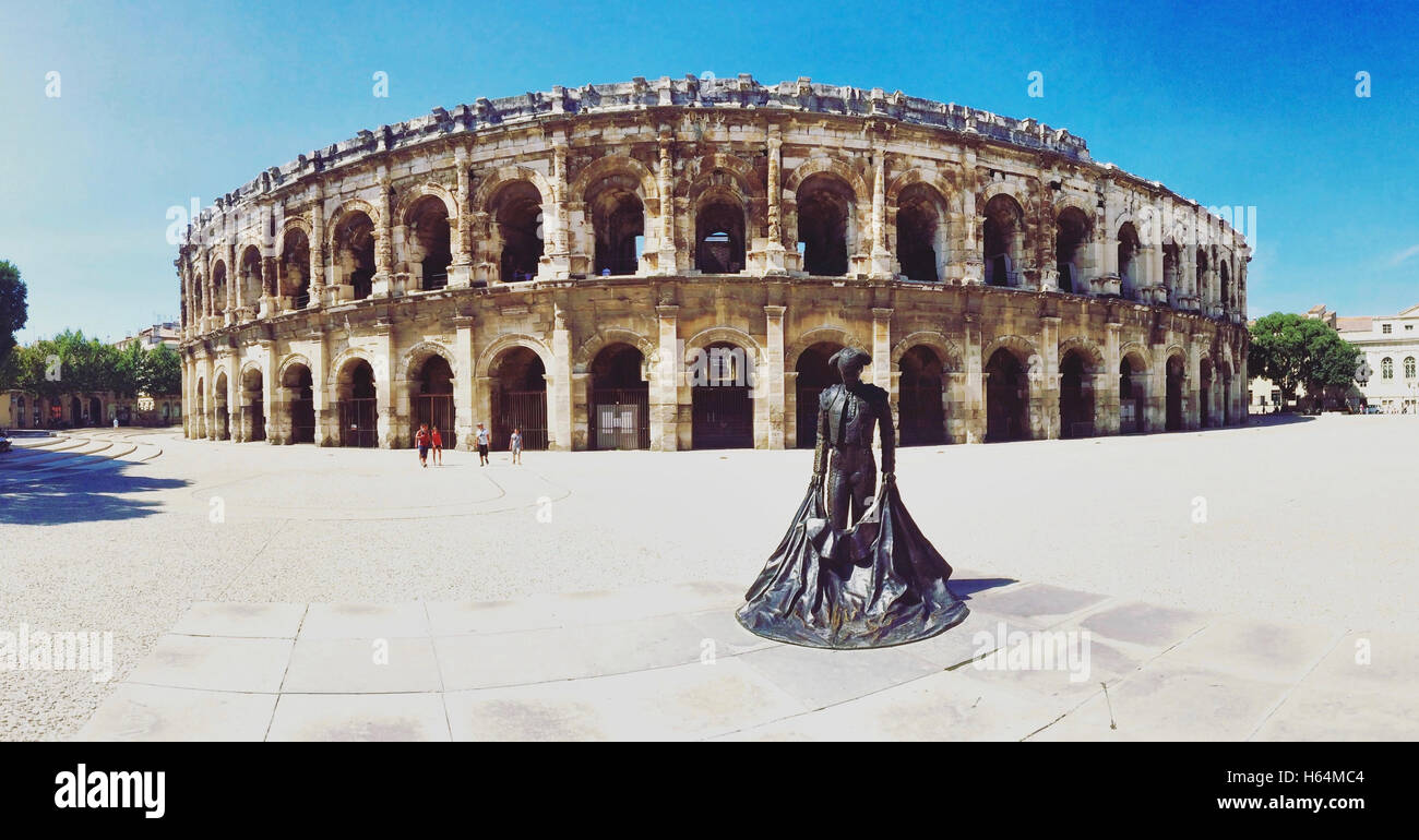 The Roman amphitheater (Roman Arena) and bullfighter statue in Nimes, France. Stock Photo
