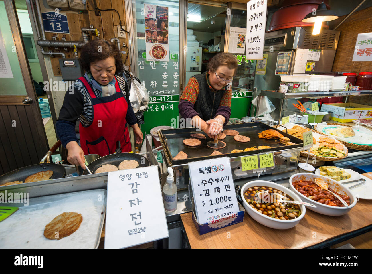 Two female vendors cooking gamjajeon (potato pancake) at a food stall in Tongin Market, Jongno-gu, Seoul, Korea Stock Photo