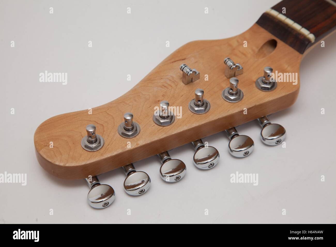 Tuners on the headstock of a maple electric guitar neck with a rosewood fretboard, roller string trees attached Stock Photo