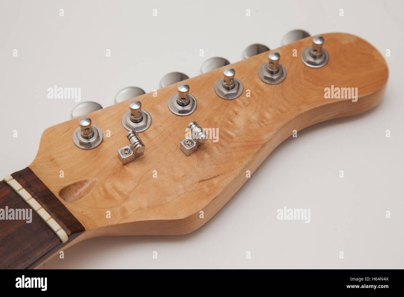 Tuners on the headstock of a maple electric guitar neck with a rosewood fretboard, roller string trees attached Stock Photo