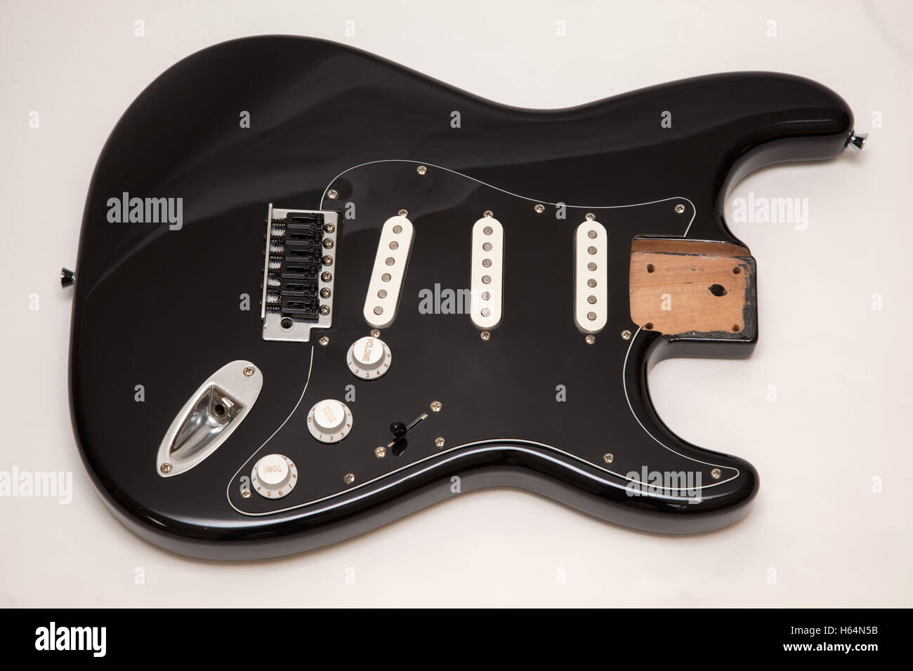 A black fender stratocaster copy electric guitar body, neck removed, tremolo arm removed Stock Photo