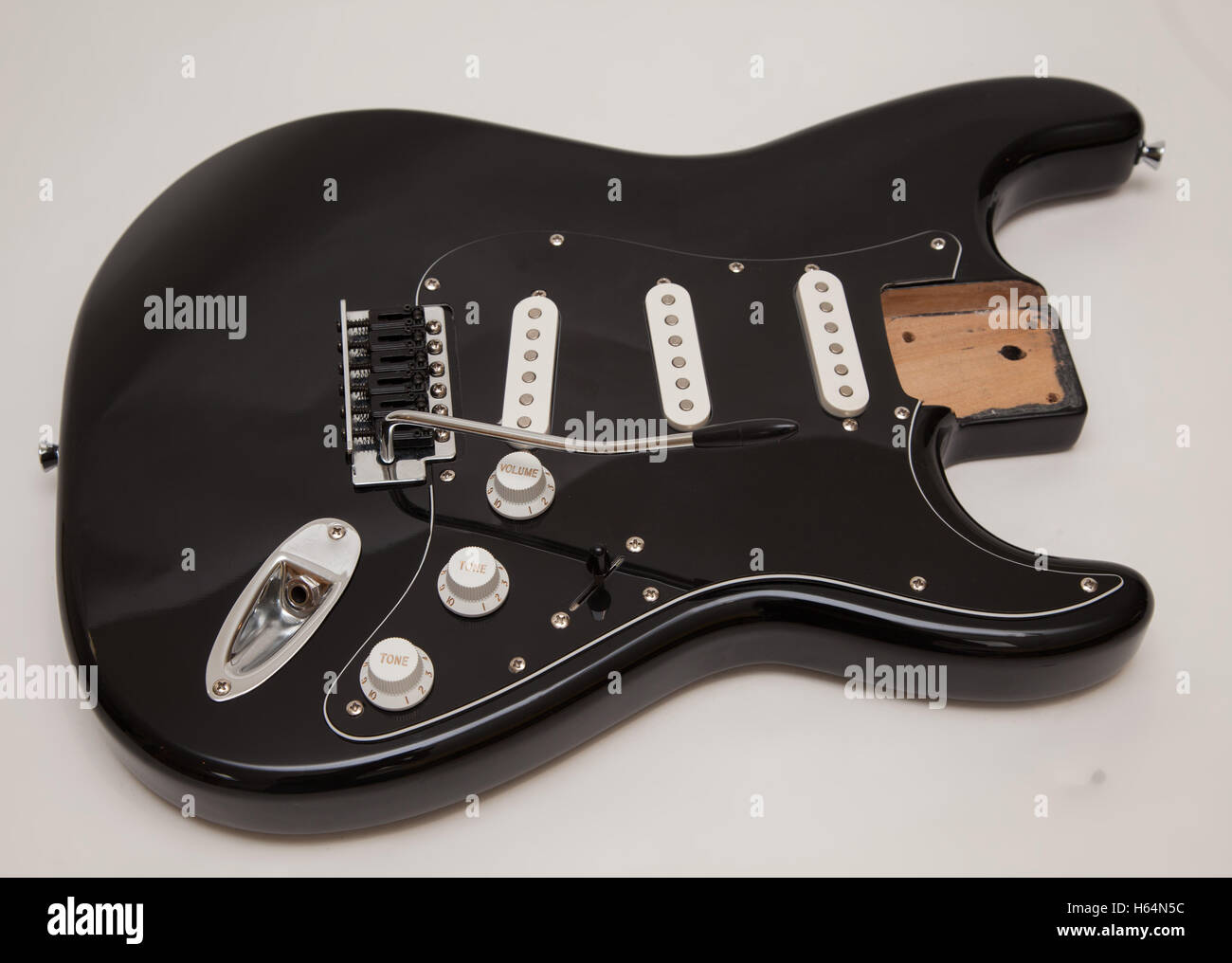A black fender stratocaster copy electric guitar body, neck removed, tremolo arm attached Stock Photo